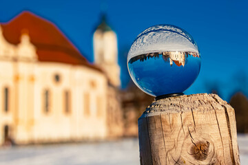 Crystal ball alpine winter landscape shot with the famous Wieskirche church at Steingaden,...