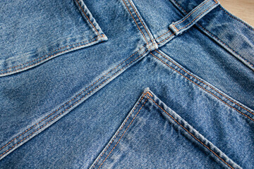 Close-up of blue denim jeans with pockets and stitch details. Background denim texture