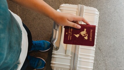 Person holding a passport and suitcase, ready for travel. Travel essentials include a passport and...