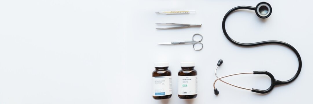 Medical tools and supplies on a white background. Includes a stethoscope, scissors, tweezers, thermometer, and medicine bottles. Essential medical equipment. Healthcare and medicine background.