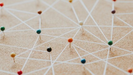 Colorful pins connected by strings on a corkboard. Pins and strings form a network. Network of pins and strings symbolizes connections and ideas. Connection background, business network background.