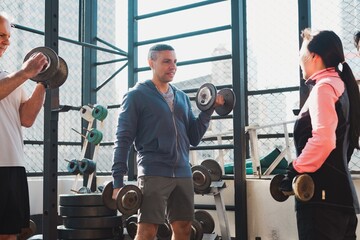 Group workout with diverse people lifting dumbbells. Fitness enthusiasts lifting weights. Gym session with diverse group lifting dumbbells together. Exercise, fitness, and workout concept.