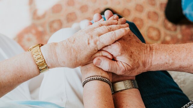 Close-up of elderly hands holding each other, symbolizing care and support. Elderly hands, care, and support are central themes in this touching image. Old couple in a retirement home.