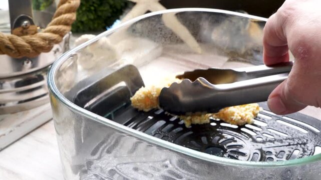 Using an air fryer to make homemade fish sticks for a quick and easy dinner,  Breaded fish sticks being cooked in an air fryer.  Easy seafood dinner meal.