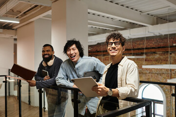 Three colleagues stand together on a balcony, engaged in cheerful conversation while sharing ideas