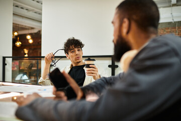 Colleagues engage in discussion over coffee in a modern office workspace