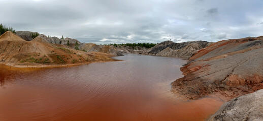 Ural Mars. An extraordinarily beautiful summer landscape with red lakes, colorful slopes and forest. A picturesque mountain range. Natural landscape, impressive sky. Nature of the Urals.