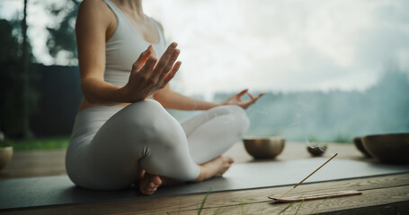 Anonymous Female Sits Cross-Legged, Meditating in a Nature Retreat, Blending with Peaceful Forest...