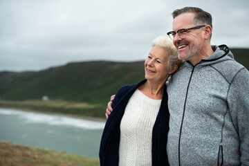 Obraz premium Happy Caucasian senior couple, man and woman, enjoying a scenic coastal view. Senior couple smiling, embracing, enjoying coastal view. Happy elderly couple, coastal view. Senior couple enjoy life