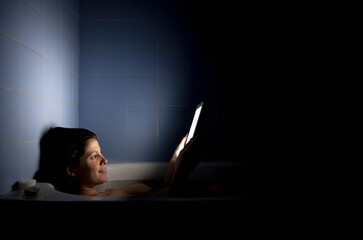 Woman Reading a Tablet in an Atmospheric Bathroom Setting