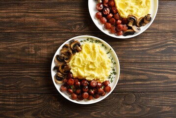 Plate of mashed potatoes with roasted sweet and spicy sausage bites and mushrooms