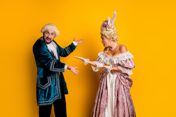 Elegant couple in antique costumes for a masquerade against a yellow background