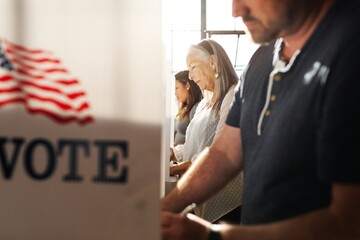 US election day, Senior American woman voting at booth at voting booth at US election station. Us...