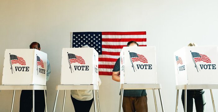 US election day, Diverse people at voting booth at US election station with American flag in background. Diverse people in line to vote at US election day. Vote for American democracy.