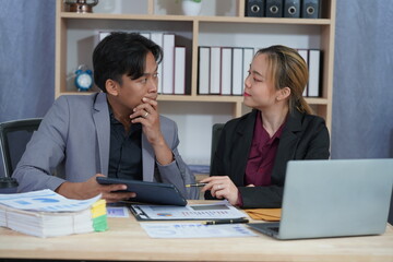 Two young Asian businessmen discuss business matters in a conference room to brainstorm ideas for a successful startup. Consulting working together with laptop computers in the office