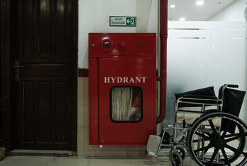 A red fire hydrant cabinet next to a wheelchair