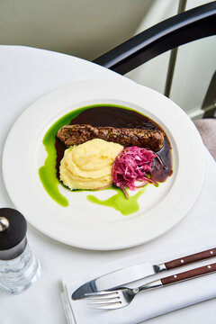 Delight in a culinary masterpiece featuring tender kebab paired with velvety smashed potatoes, complemented by bright pickled cabbage. The dish showcases vibrant colors and exquisite flavors