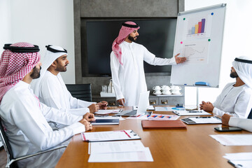 Arab businessmen wearing emirati and saudi kandura meeting in office for business deal - Corporate...