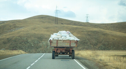 Tractor carrying sacks of produce along a road.