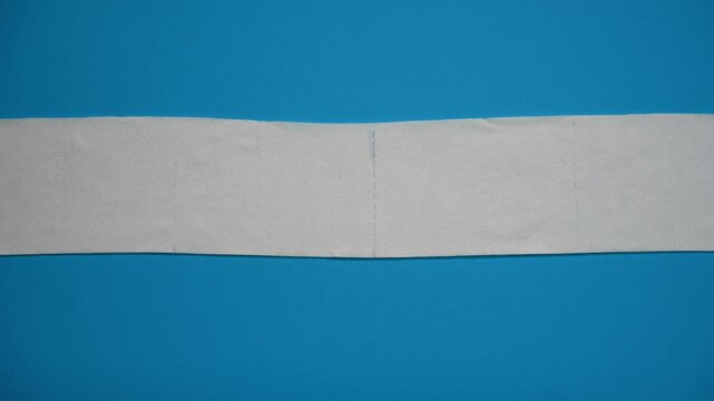 Top view of white toilet paper unrolls in different directions on a blue background