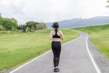 A joyful young woman jogging through a public park with a smile on her face.