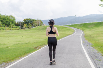 A joyful young woman jogging through a public park with a smile on her face.
