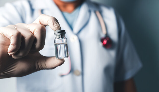 Close-up of a healthcare professional wearing gloves and uniform, holding a clear medical vial containing vaccine or medication.