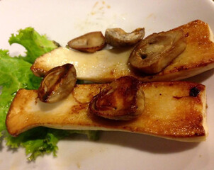 Grilled straw mushrooms and eryngii mushrooms on white plate