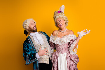 Elegant Couple in Period Costumes Enjoying a Lighthearted Moment on a Vibrant Background