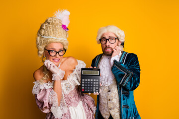 Two individuals dressed in vintage royal costumes holding a calculator, juxtaposing historical...