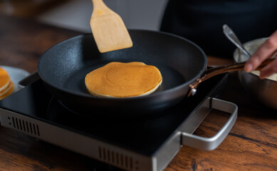 Woman chef flipping pancakes in pan.