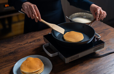 Woman chef flipping pancakes in pan.