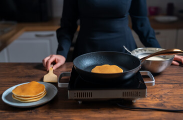 Woman chef cooking pancakes in pan.