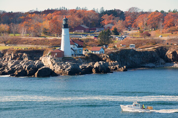 Portland Head Light in Cape Elizabeth, Maine as seen from the Atlantic Ocean on an autumn morning with trees in fall colors. An historic 1791 lighthouse still in operation.