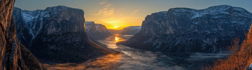Fototapeta premium A stunning panoramic view of a misty valley at sunrise, framed by imposing mountains and vibrant light.