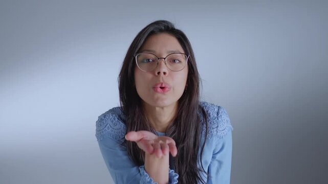 Woman in glasses, blue shirt, covering mouth, symbolizes silence, contemplation, or secrecy, shot from chest up, evoking introspection.