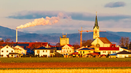 Winter far view near sunset or sundowner with a church and a sugar factory chimney near...