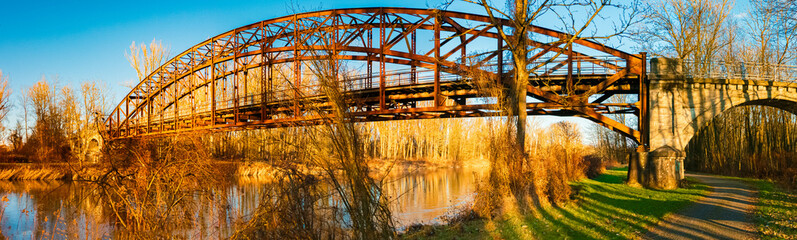 Winter landscape with an old railway bridge and reflections on a sunny evening near Landau an der...