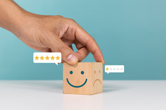 Service rating, satisfaction and positive feedback concept. Hand flip wooden cube change smile face emoticon give a five star indicates the highest level of satisfaction