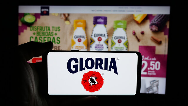 Stuttgart, Germany - 04-09-2025: Person holding cellphone with logo of Peruvian dairy company Gloria S.A. on screen in front of webpage. Focus on phone display.