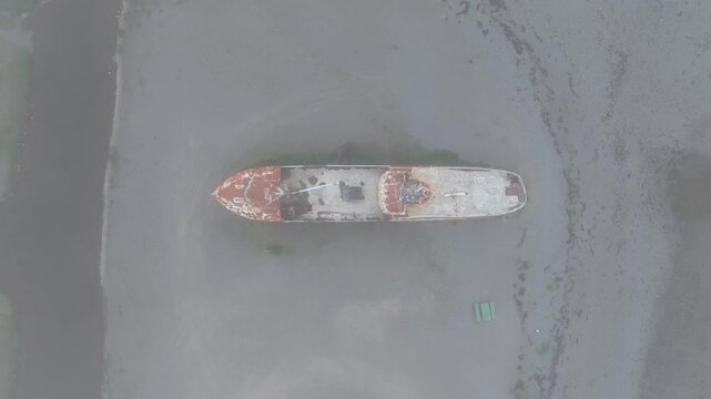 Aerial top-down view of the rusted Gardar BA 64 shipwreck beached on the black sands of Iceland, surrounded by muted textures and natural tones.