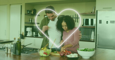 Image of heart icon over happy diverse couple cooking