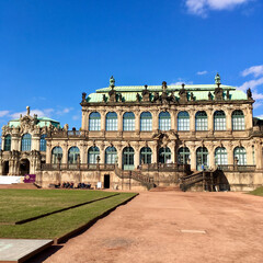 Fototapeta premium The Zwinger Palace, a magnificent baroque masterpiece in Dresden, Germany, showcases its intricate design and stunning architecture under the clear blue sky.