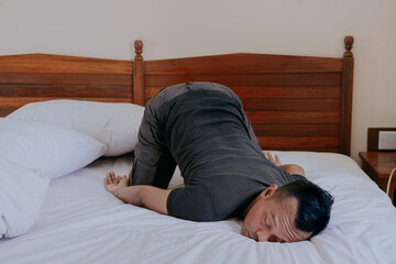 Weird and funny sleep pose of Asian man in his bedroom at home in boring day off.