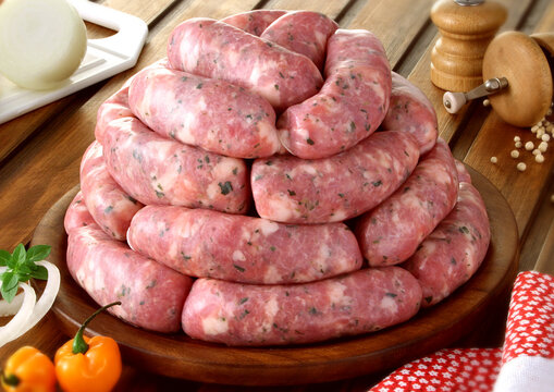 mesa de madeira com prato com lingui&ccedil;a de pernil crua 