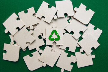 Recycling Symbol Puzzle Piece Among Scattered Elements. jigsaw puzzle pieces on green background...