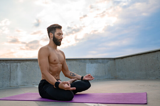 attractive hansome man with athletic strong body doing morning yoga dzen meditation
