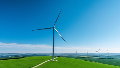 Tall wind turbines stand in a vibrant green field, harnessing wind energy in a rural area during a clear day. The blue sky complements the peaceful surroundings
