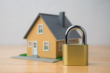 Padlock and house model on wooden table with white wall background. Home insurance, house security...