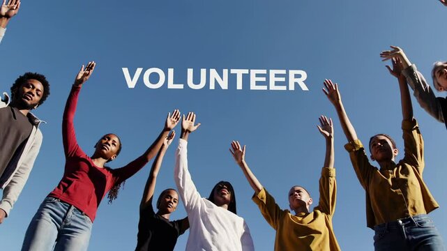Diverse group of volunteers raising their hands against a clear blue sky, symbolizing unity, teamwork, and commitment to social contribution